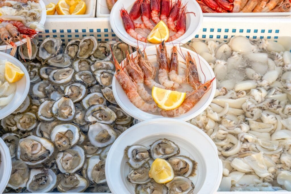 Boat to Bar: The Journey of Fresh Seafood at Gallier’s 2 Raw clams, oysters, and prawns displayed in bowls with lemon wedges