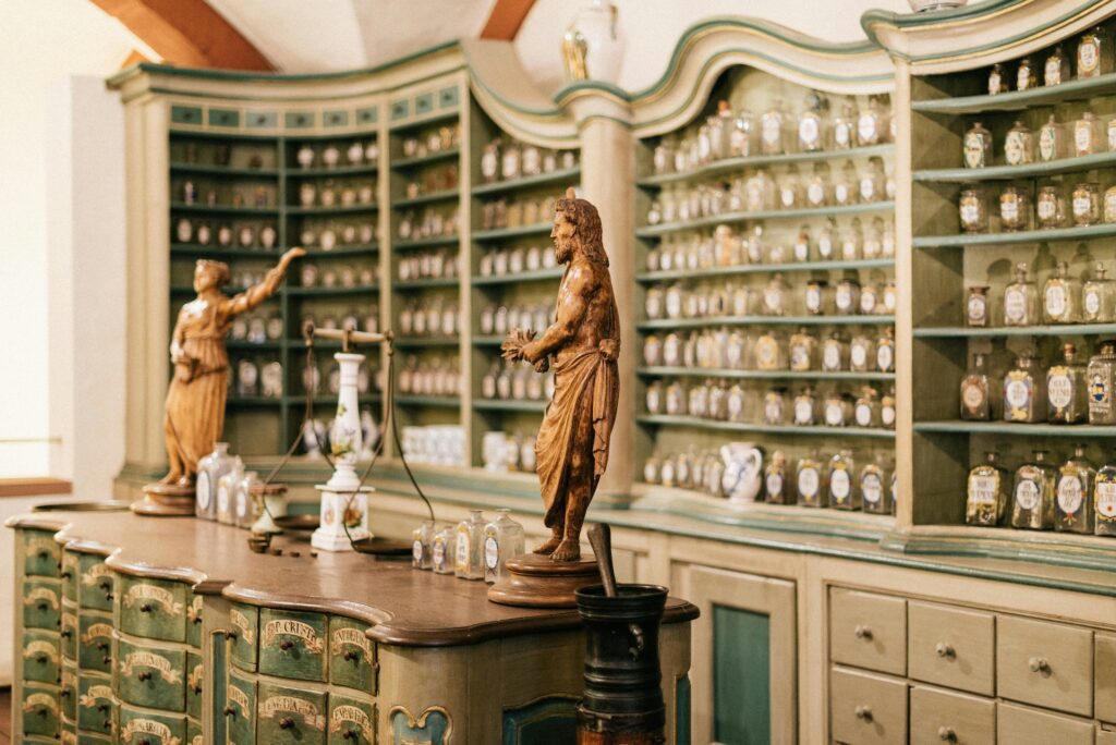 Antique pharmacy interior with wooden statues and glass jars