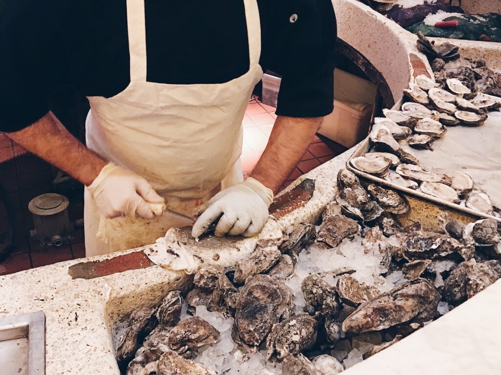 Oyster shucker preparing oysters behind bar