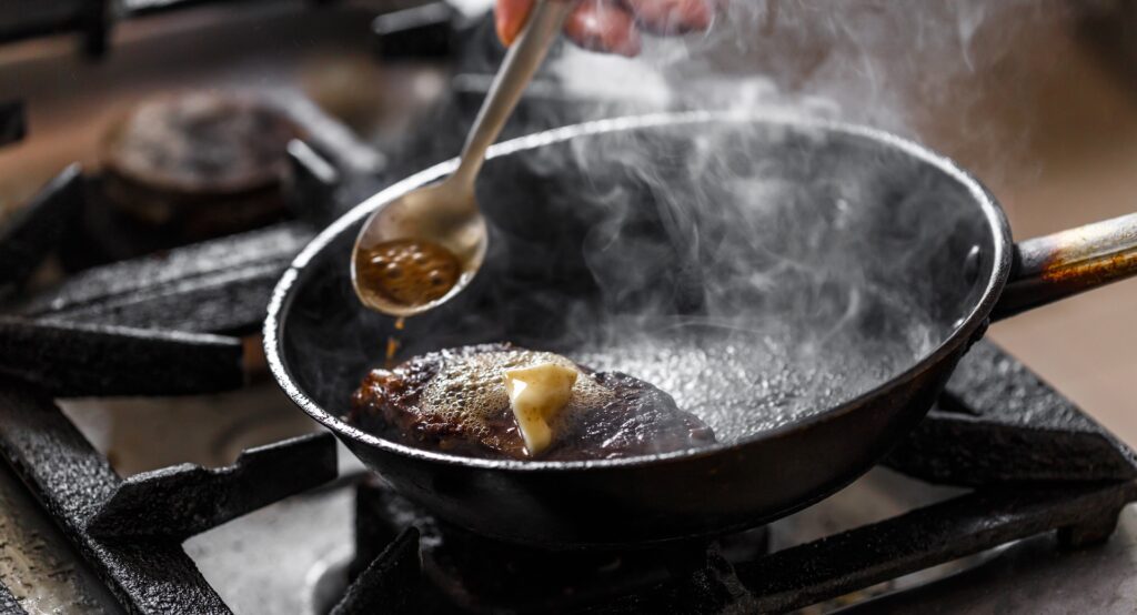 The Role of Roux and Stock in Southern Dishes 3 Pan-seared meat with butter and steam rising, symbolizing the slow, flavor-building process of Southern cuisine.