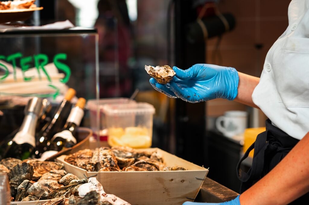 Chef holding freshly opened oyster in kitchen