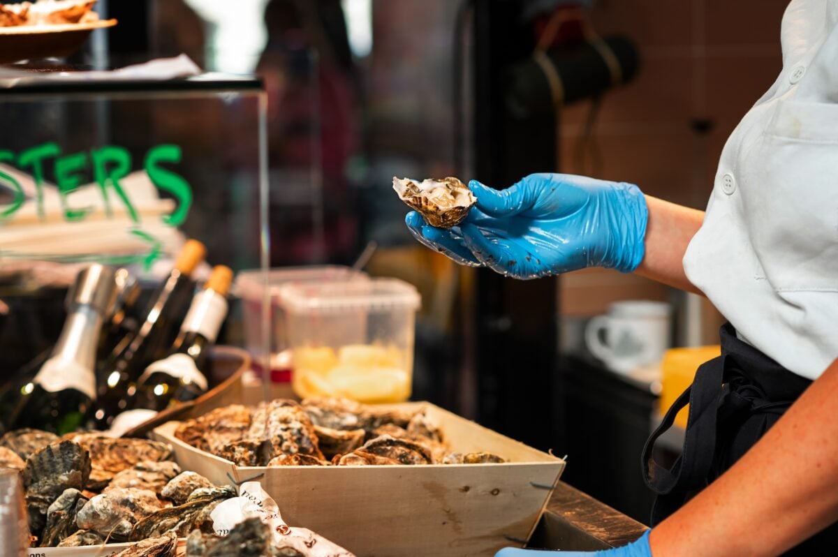 Chef holding freshly opened oyster in kitchen
