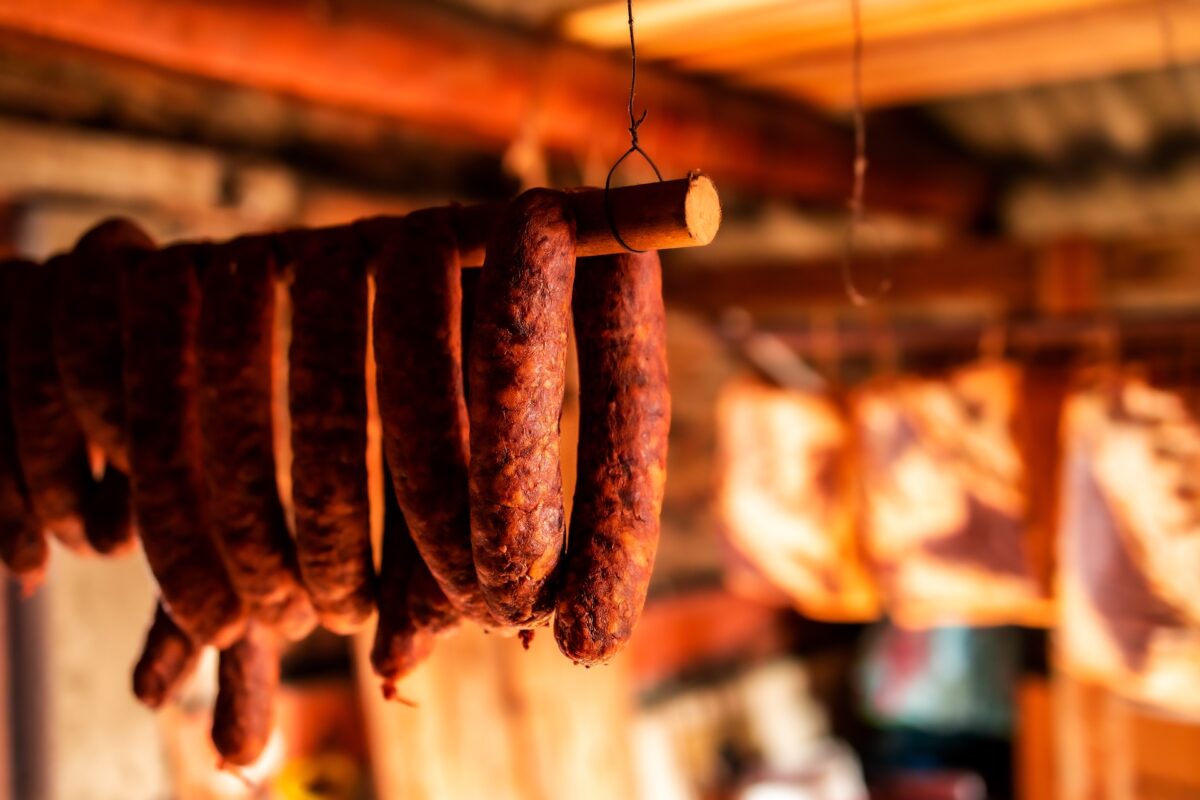 Smoked andouille sausages hanging in a rustic smokehouse