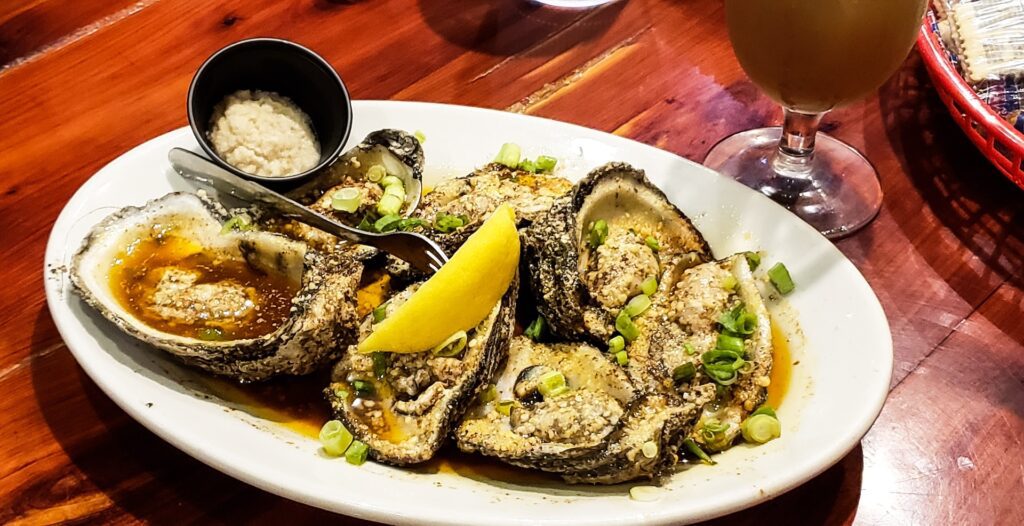 Charbroiled oysters served with garlic butter and Parmesan on a wooden table in New Orleans.