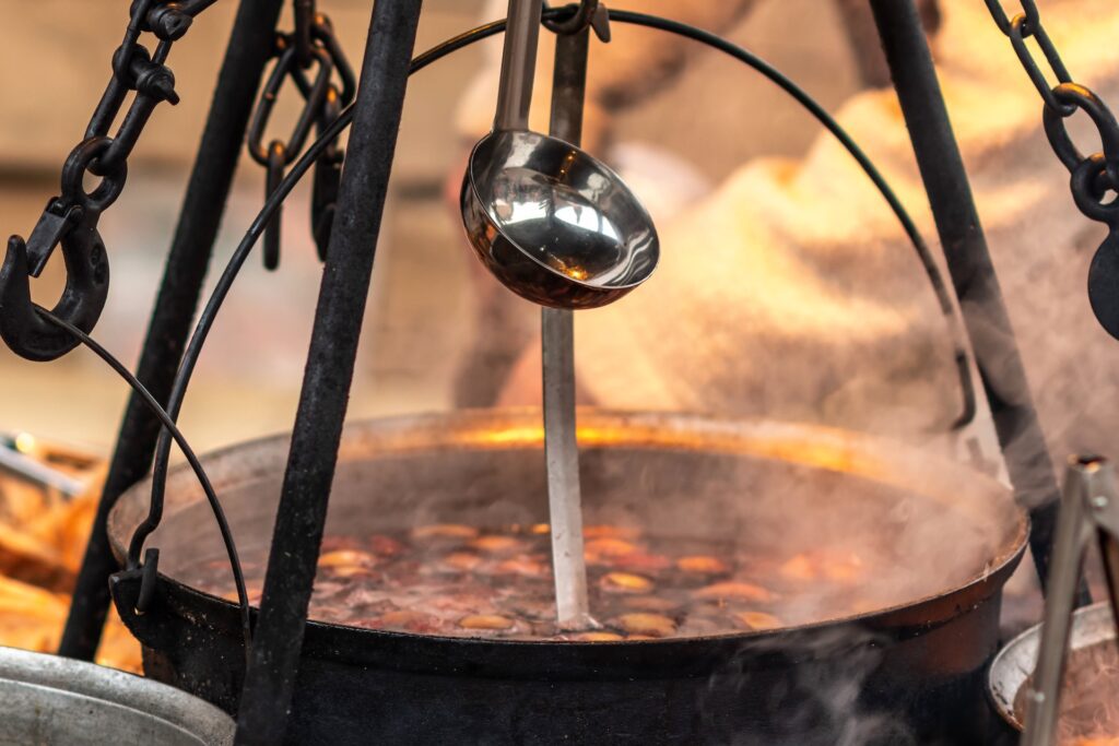 Chicken and Andouille Sausage: A Cajun Power Combo 2 Steaming pot of chicken and sausage stew cooking over open fire