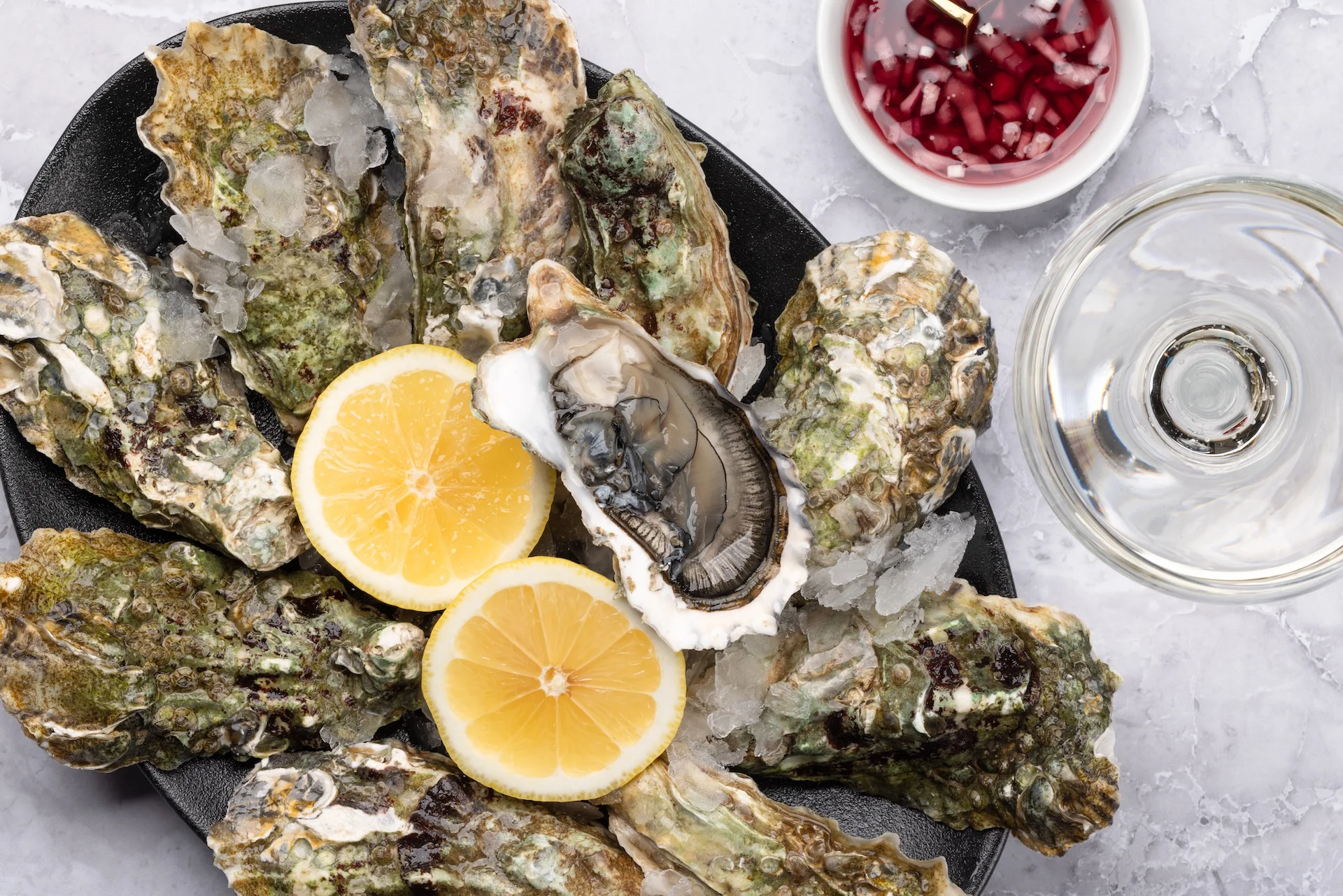 Plate of fresh oysters on ice with lemon wedges
