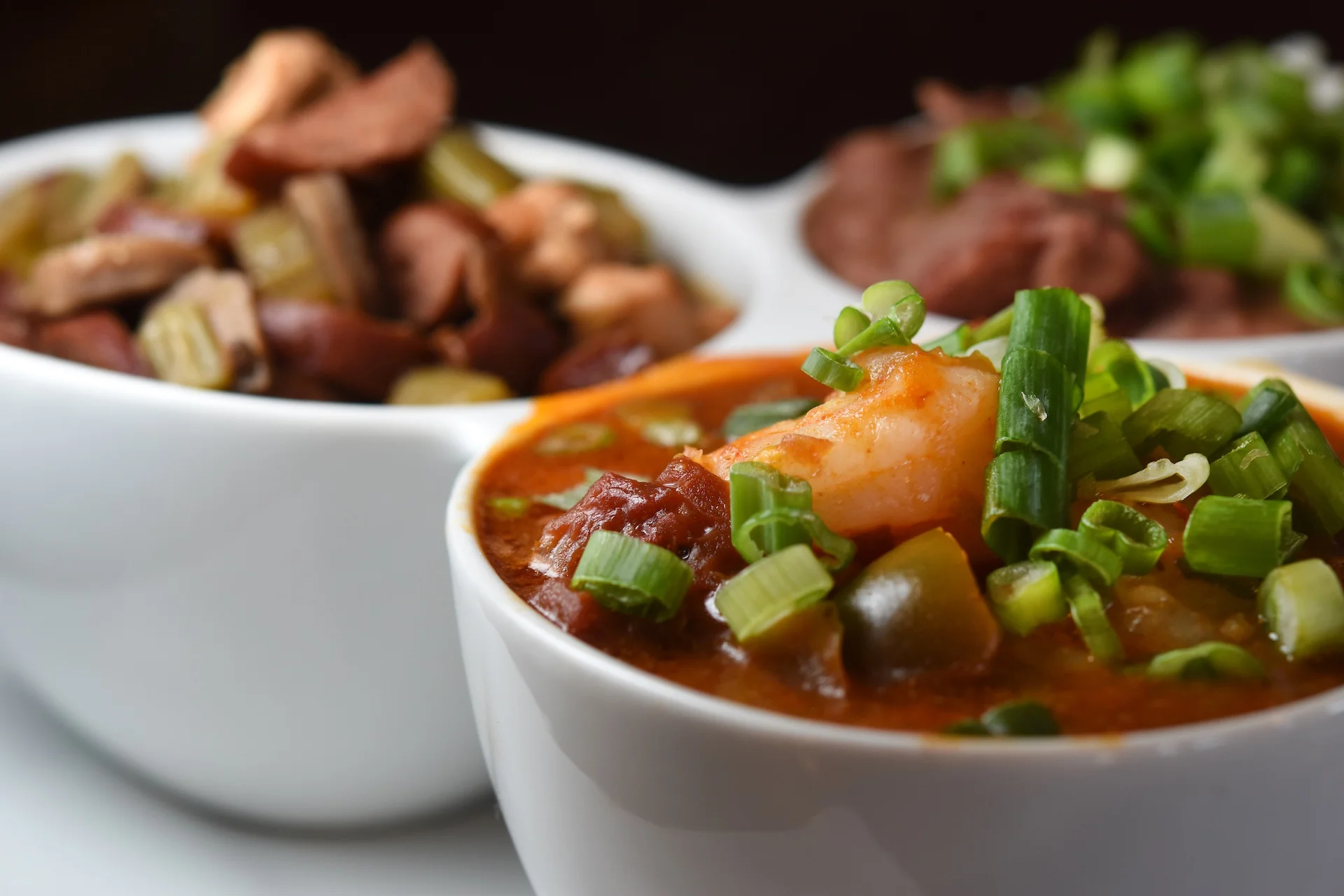 Close-up of a bowl of seafood gumbo with shrimp and green onions
