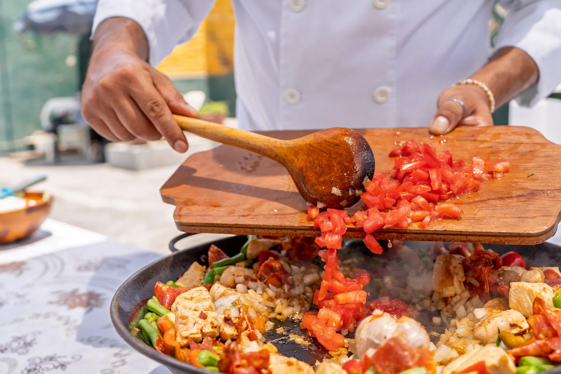 Chef adding diced tomatoes to a pan of Cajun ingredients