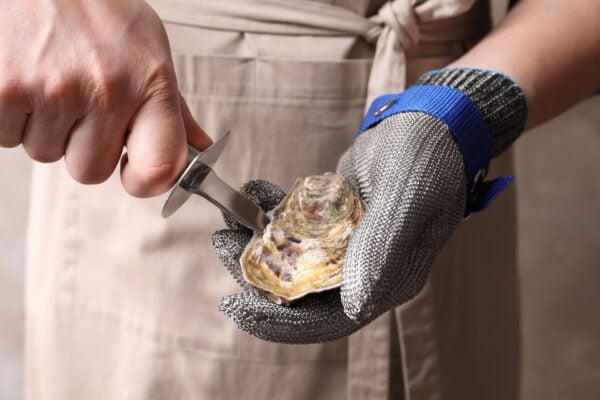 A Beginner’s Guide to Eating Oysters in New Orleans 8 Hand holding a freshly shucked raw oyster served on ice in New Orleans