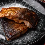 Blackened redfish searing in a cast iron skillet with butter and Cajun spices