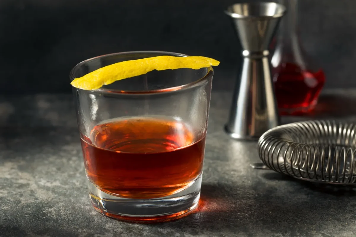 Classic Sazerac cocktail in a rocks glass with lemon peel on a dark bar counter