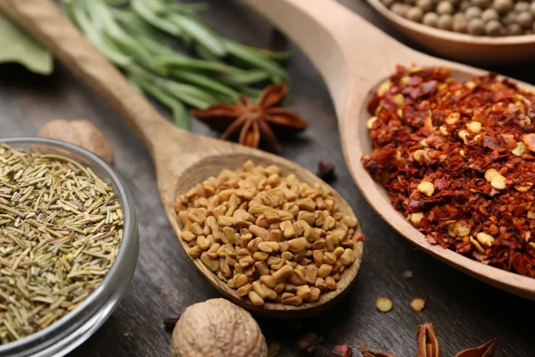 Cajun vs Creole: What's the Real Difference? 1 Aromatic Cajun and Creole spices and herbs in wooden spoons on rustic table