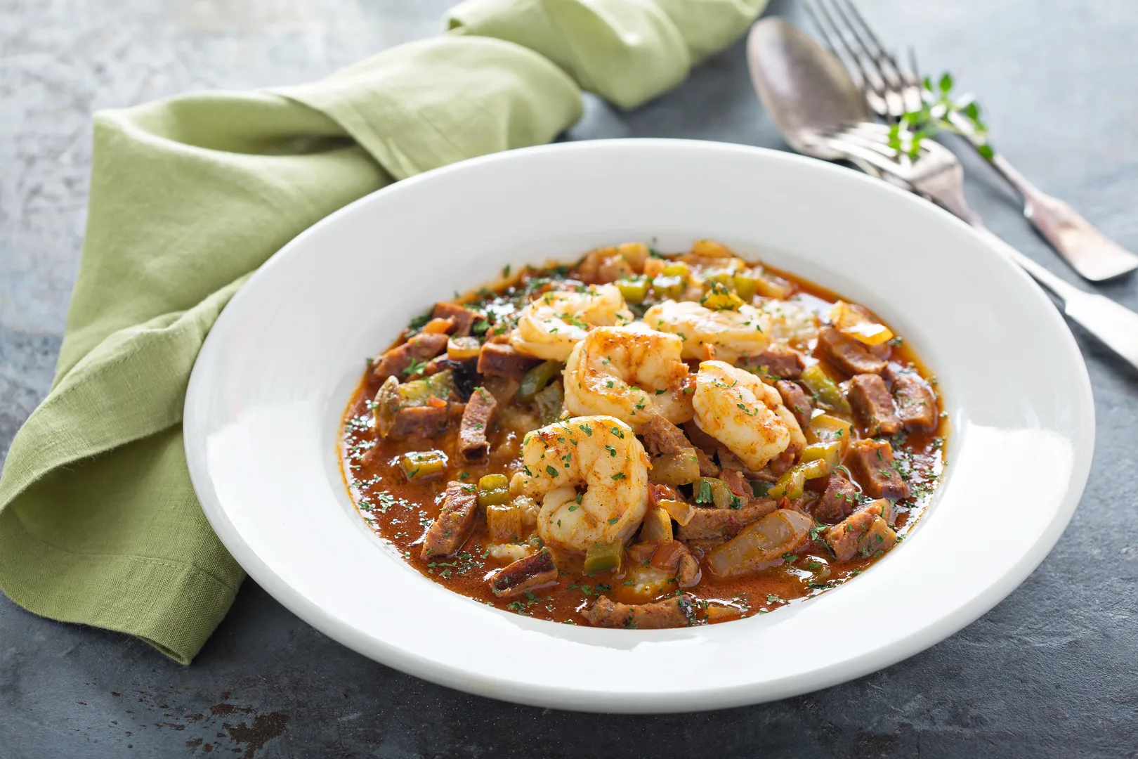 Southern-style shrimp and grits with andouille sausage and bell peppers in a white bowl