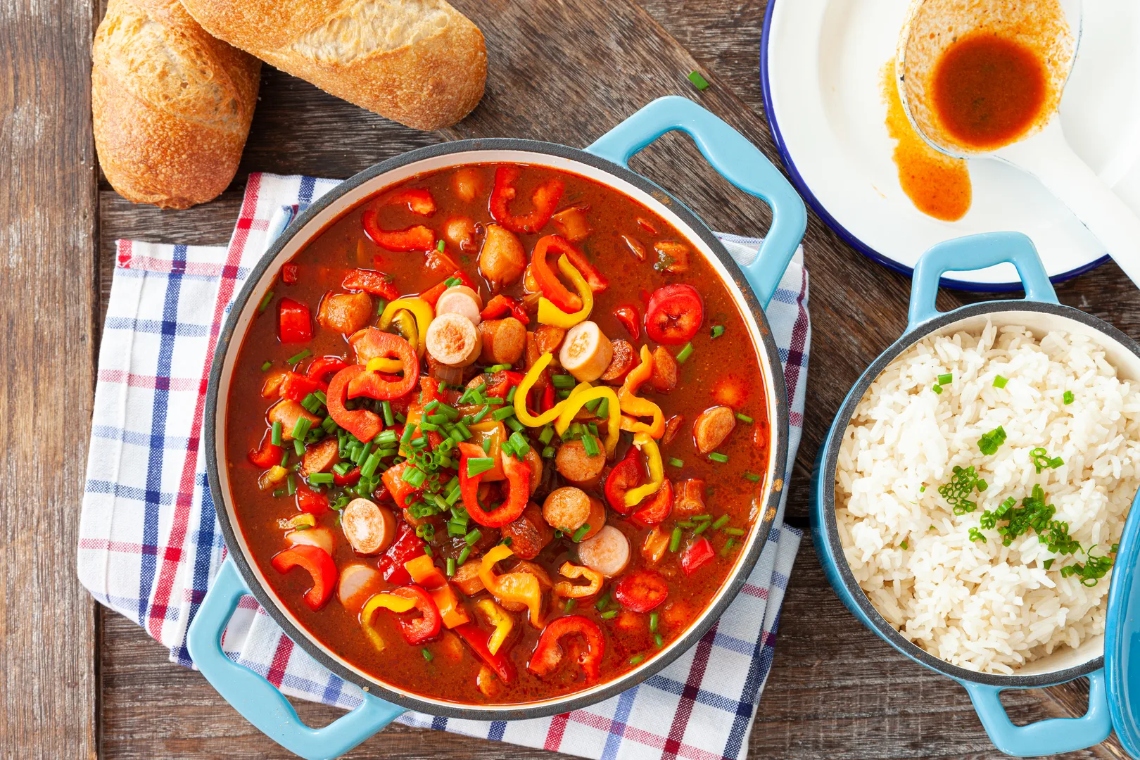 Hearty sausage and pepper stew with rice and cornbread on a rustic wooden table