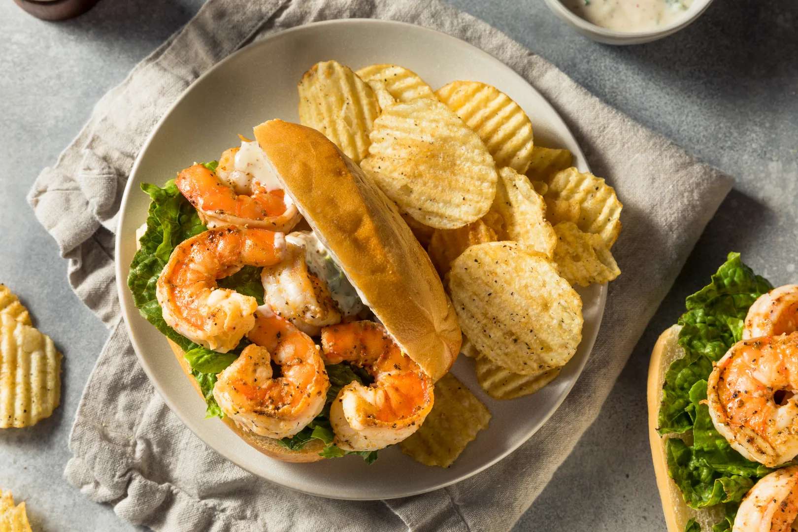 Southern shrimp po boy sandwich with lettuce and chips served on a plate