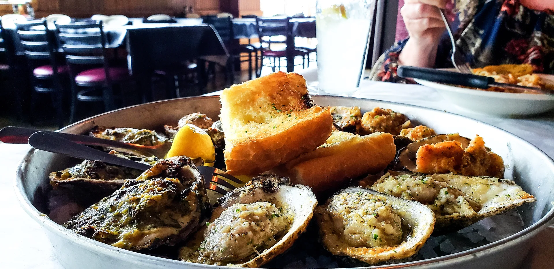 Assorted baked oyster preparations with cornbread on a serving platter at a restaurant