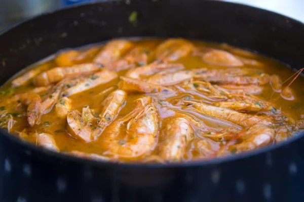 Spicy shrimp etouffee simmering in a dark pot with rich golden broth