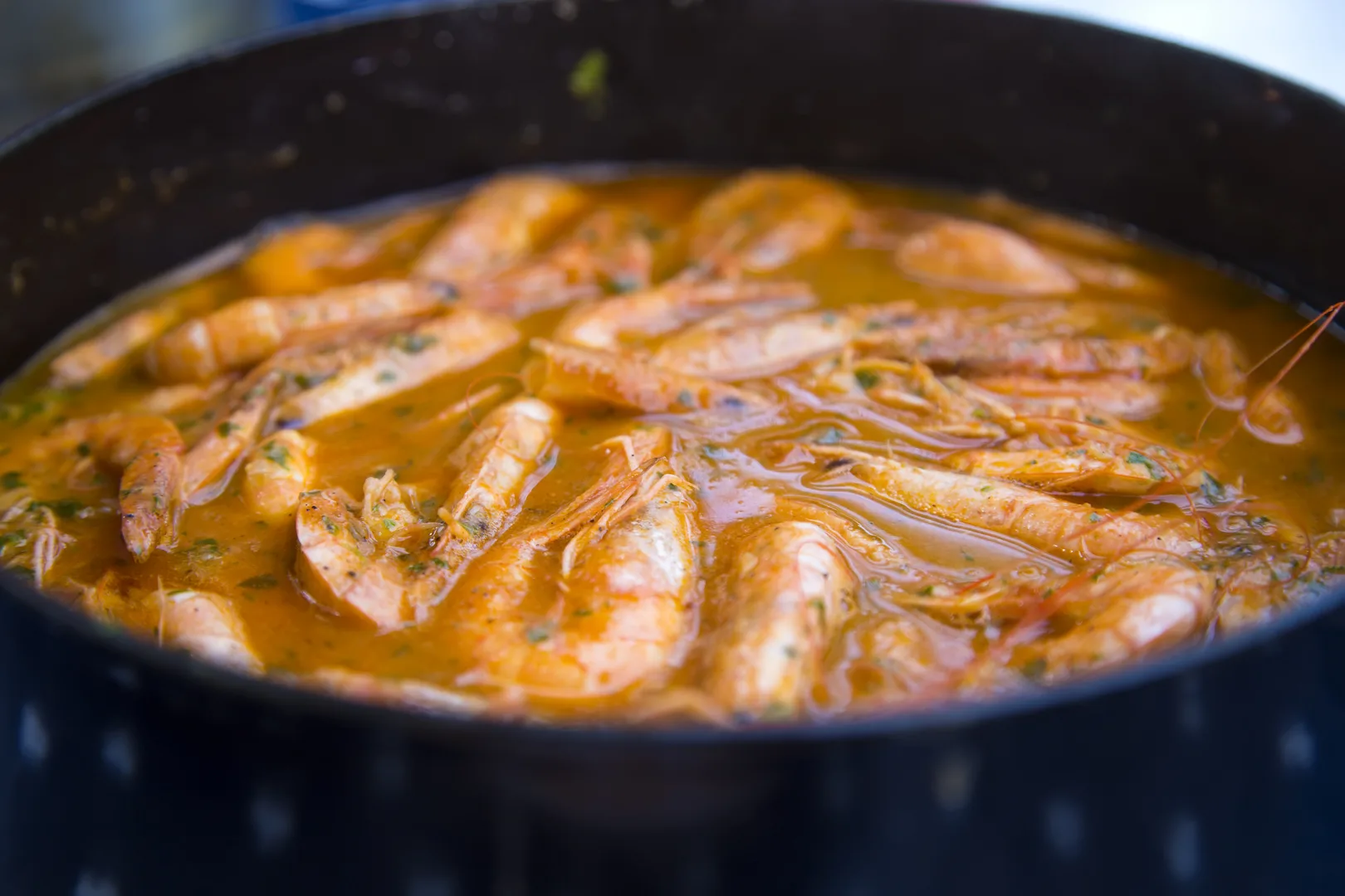 Spicy shrimp etouffee simmering in a dark pot with rich golden broth